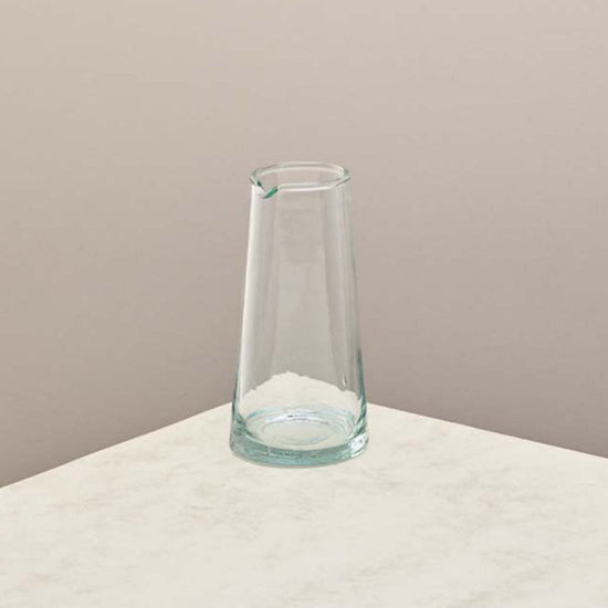 A tall glass jug on a taupe background