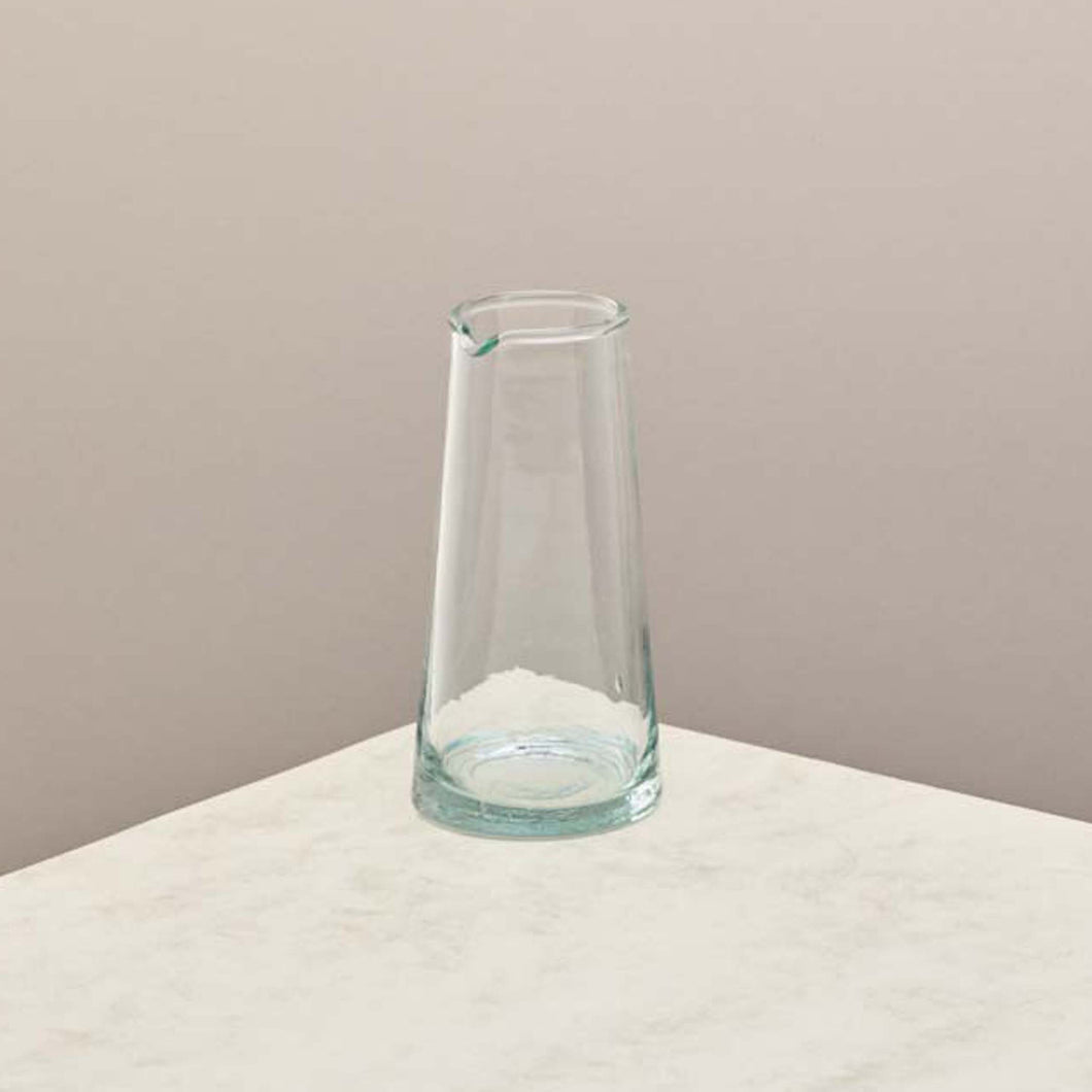 A tall glass jug on a taupe background