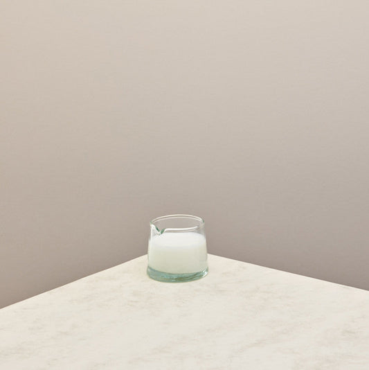 A low jug filled with milk on a taupe background