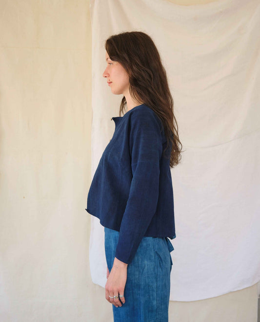 Woman wearing a blue top and jeans against a plain background