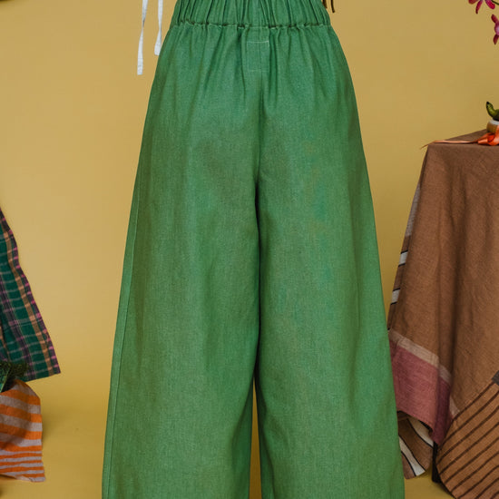 Green wide-leg pants worn by a person on a yellow background