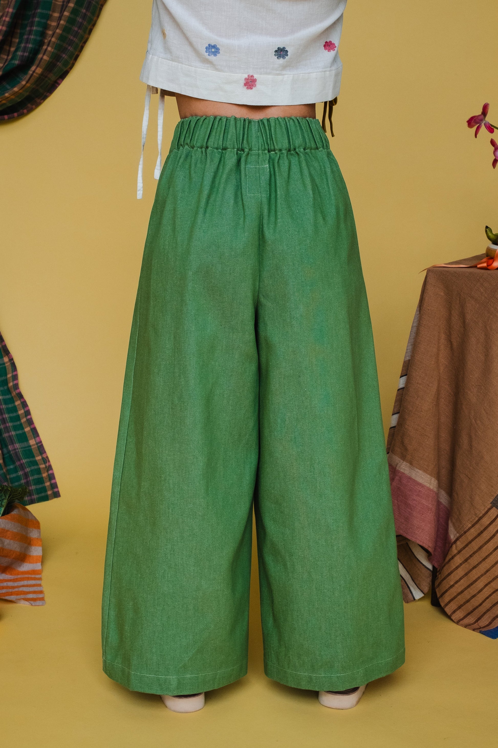 Green wide-leg pants worn by a person on a yellow background