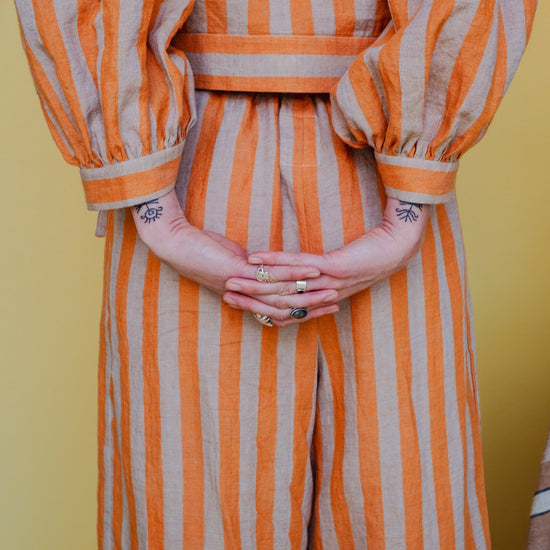 Person wearing an orange and white striped outfit with a yellow background