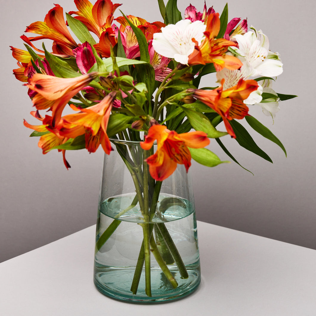 Clear glass vase with colorful flowers on a neutral background