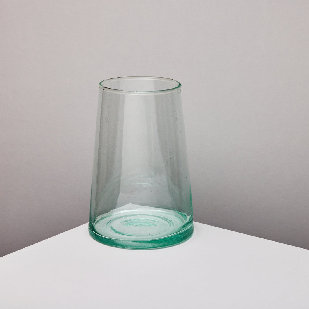 Clear glass vase on a white surface with a taupe background