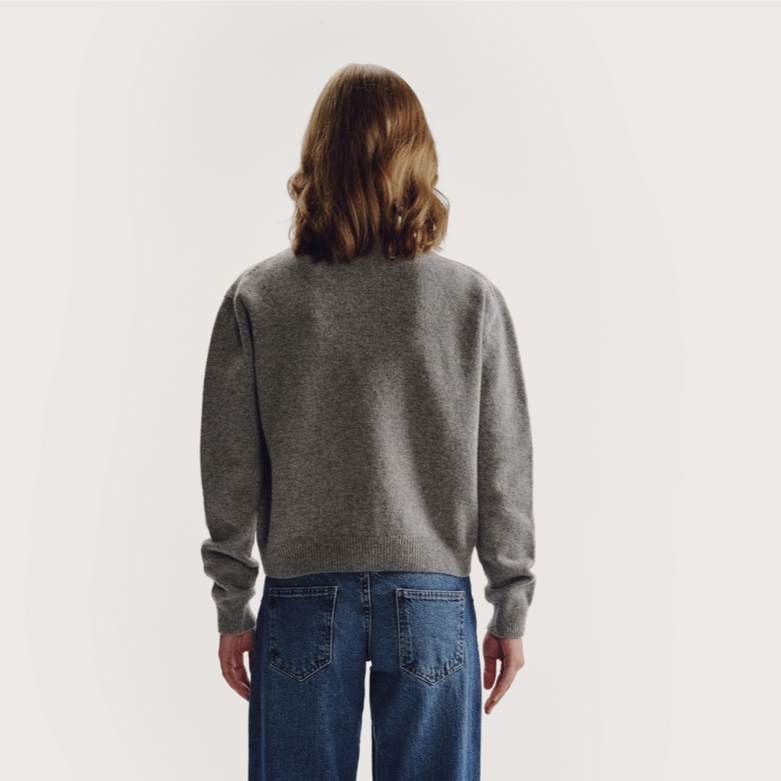 Person wearing a gray sweater and blue jeans on a plain background