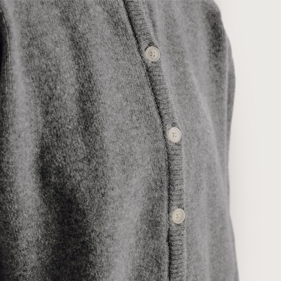Close-up of a gray cardigan with button details on a light gray background