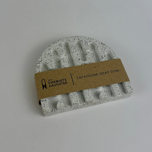 Speckled gray soap dish with a brown label on a light gray background