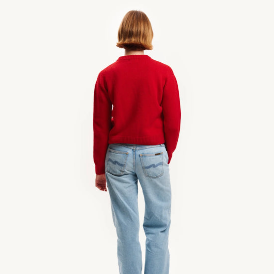 Person wearing a red sweater and light blue jeans on a white background