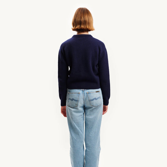 Person wearing a navy sweater and light blue jeans on a white background