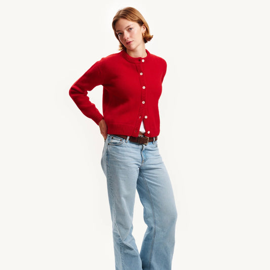 Person wearing a red cardigan and light blue jeans on a white background