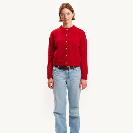 Person wearing a red cardigan and light blue jeans on a white background