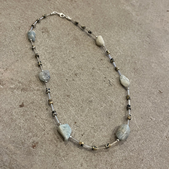 Necklace with blue and speckled beads on a concrete surface