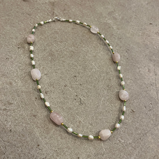 Necklace with pink and pearl beads on a concrete surface