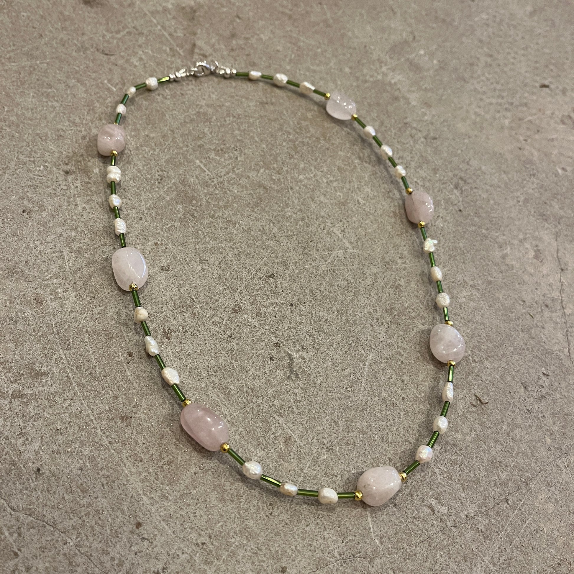 Necklace with pink and pearl beads on a concrete surface