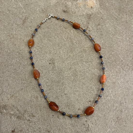 Necklace with brown and blue beads on a concrete surface