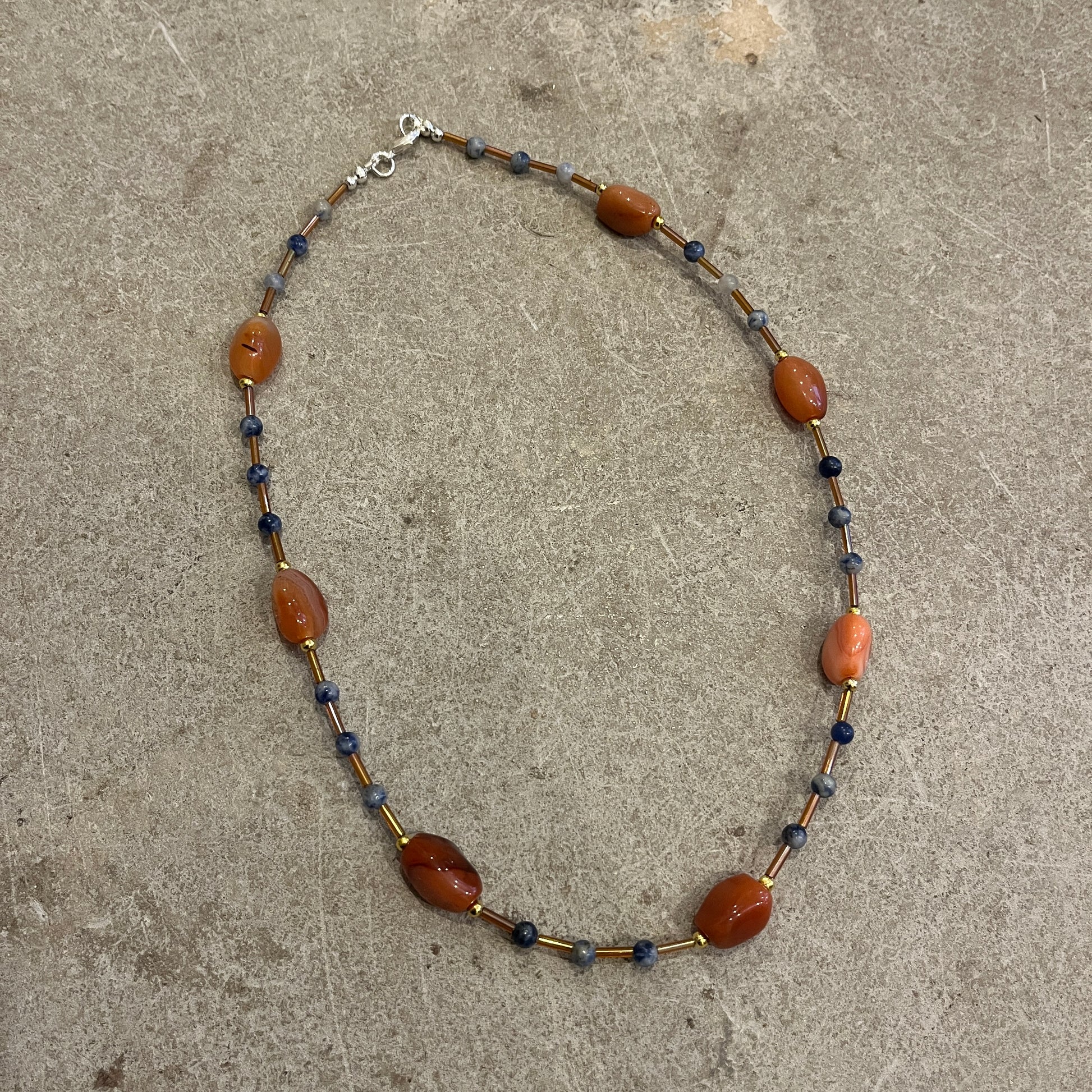 Necklace with brown and blue beads on a concrete surface