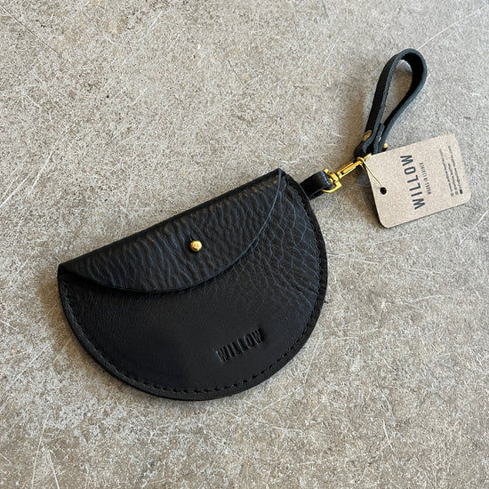 Three leather keyring purses in black, brown, and blue colors, displayed on a textured surface, each with a tag showing the brand name 'Willow Leather'.
