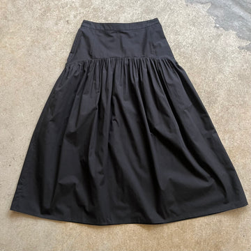 Black high waisted skirt on a textured beige surface