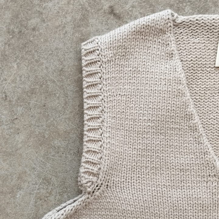 Close-up of a beige knitted sleeveless garment on a concrete surface