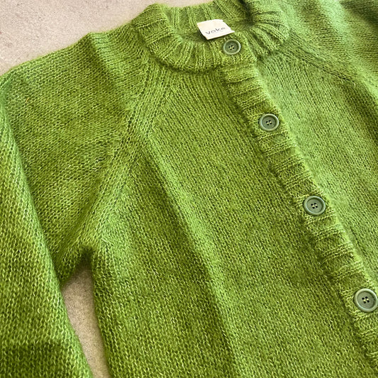 Green knitted cardigan with button details on a neutral background