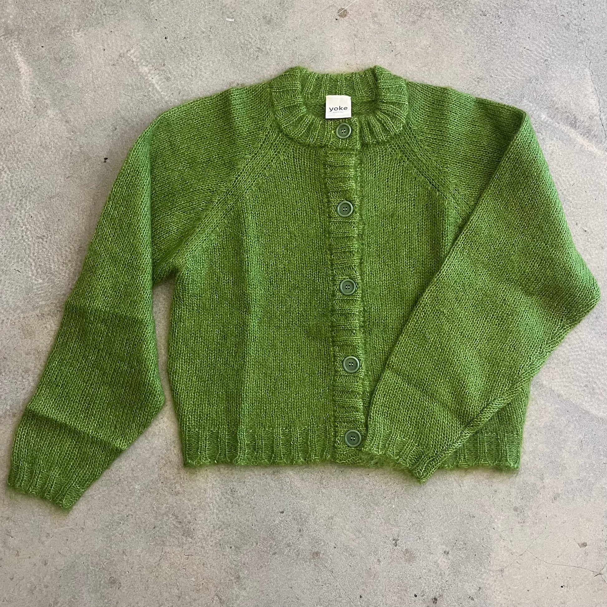 Green knitted cardigan on a concrete surface
