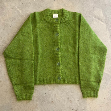 Green knitted cardigan on a concrete surface