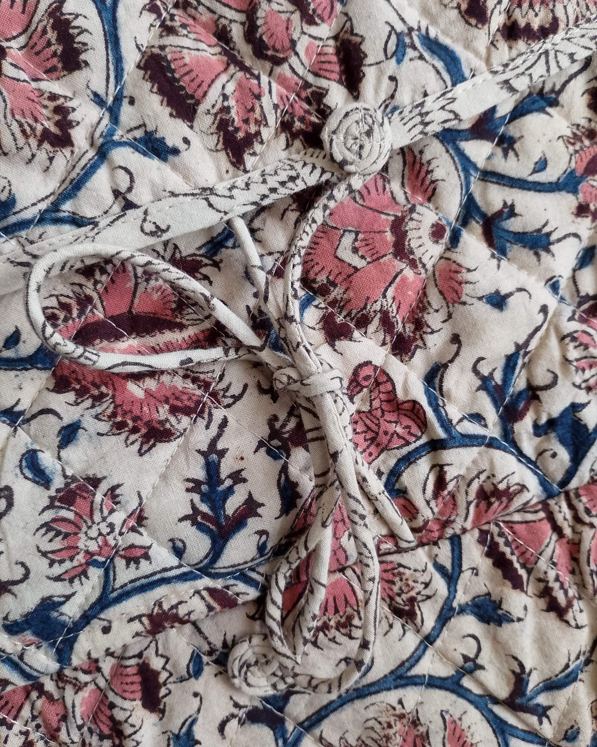 Close-up of floral patterned fabric with pink and blue colors on a white background