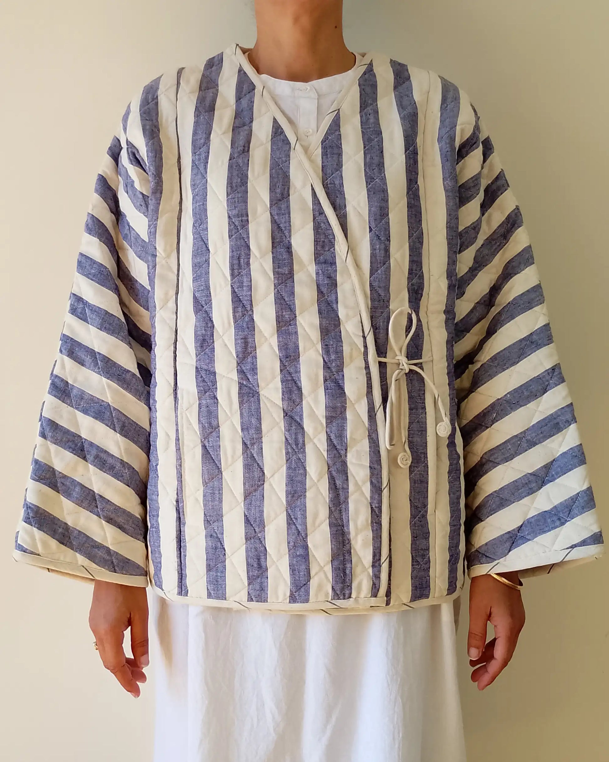 Person wearing a blue and white striped shirt with a plain background