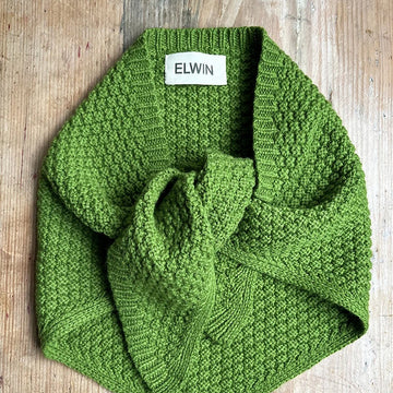 green knitted triangle scraf on wooden background