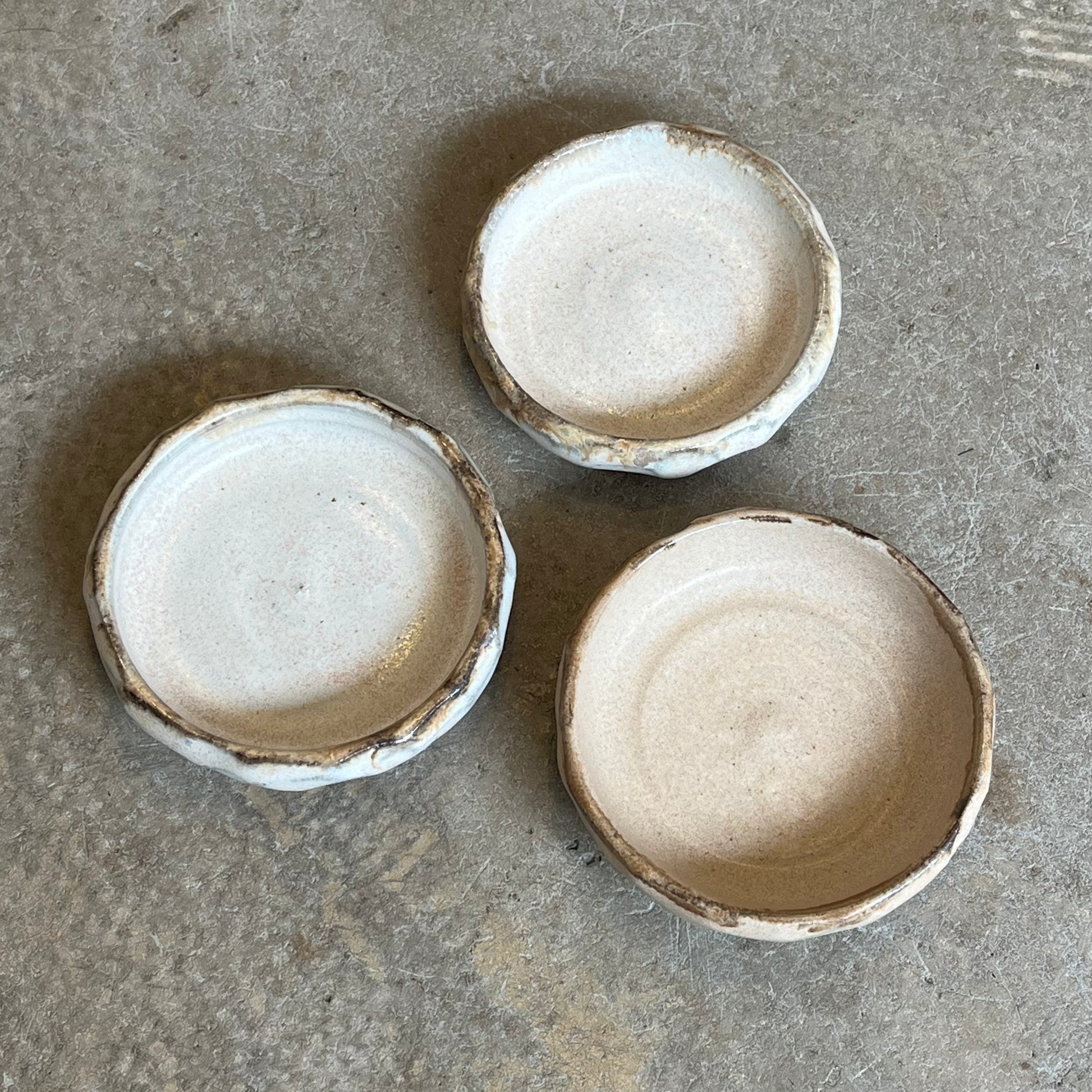Three small ceramic bowls on a textured gray surface