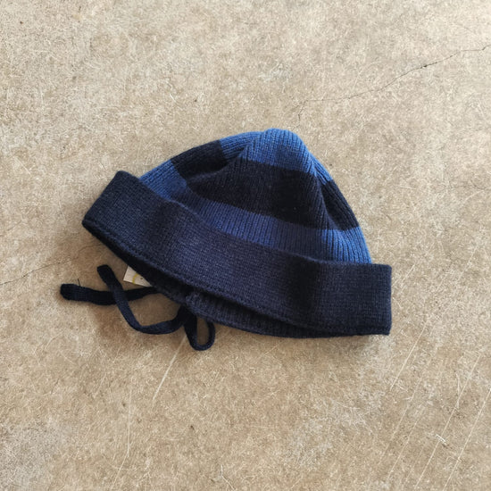 Blue and black striped beanie on a beige surface