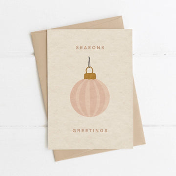 Greeting card with a pink ornament and 'Seasons Greetings' text on a beige background