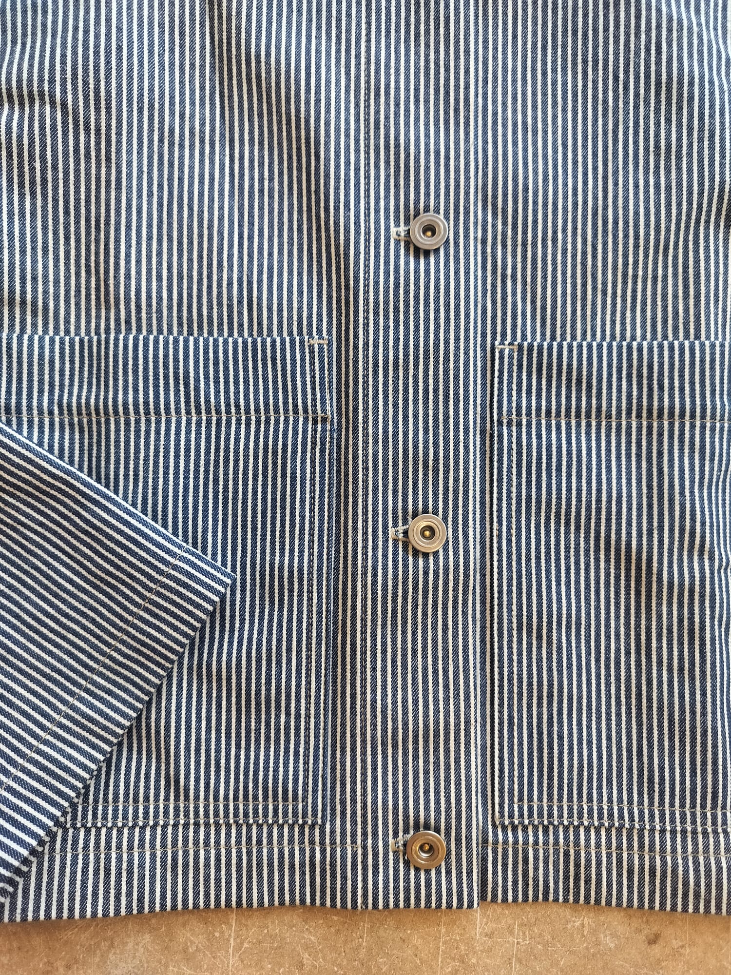 Close-up of a striped shirt with buttons on a wooden surface