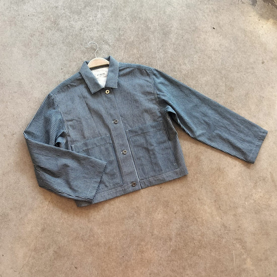 Blue denim jacket on a hanger against a concrete floor background