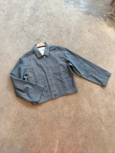Load image into Gallery viewer, Blue denim jacket on a hanger against a concrete floor background