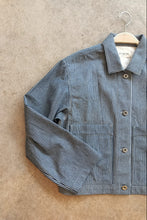 Load image into Gallery viewer, Blue and white striped workwear jacket on a hanger against a beige background