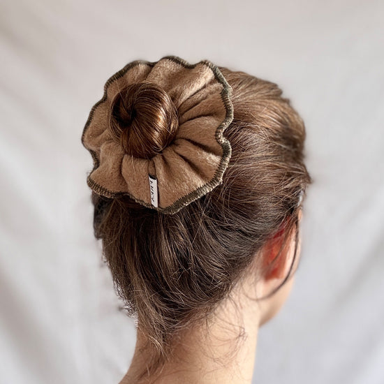 Brown hair scrunchie on a bun against a plain background