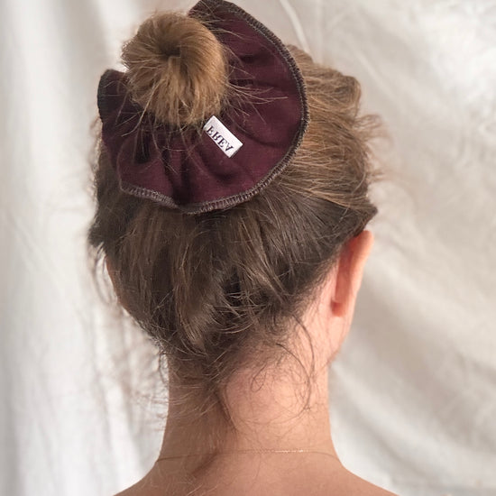 Person with a purple scrunchie in their hair on a white background