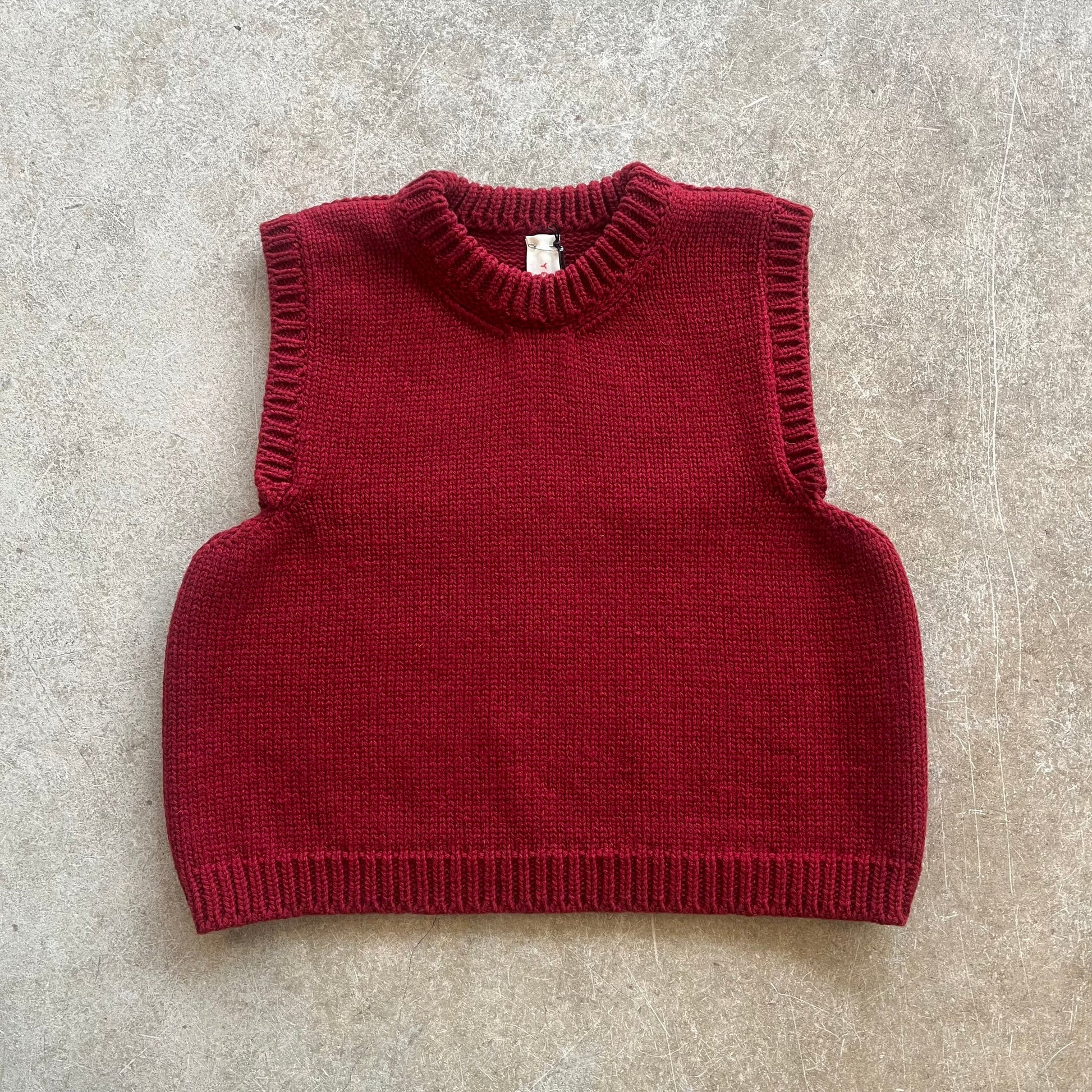 A red knitted vest on a beige background