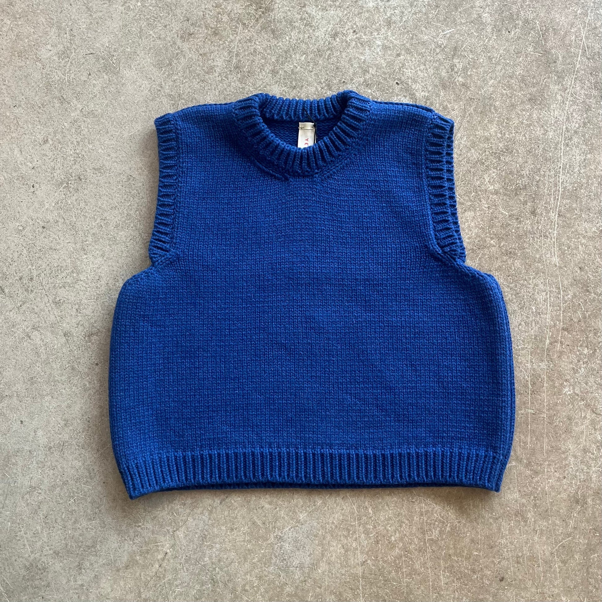 a blue knitted vest on a beige background
