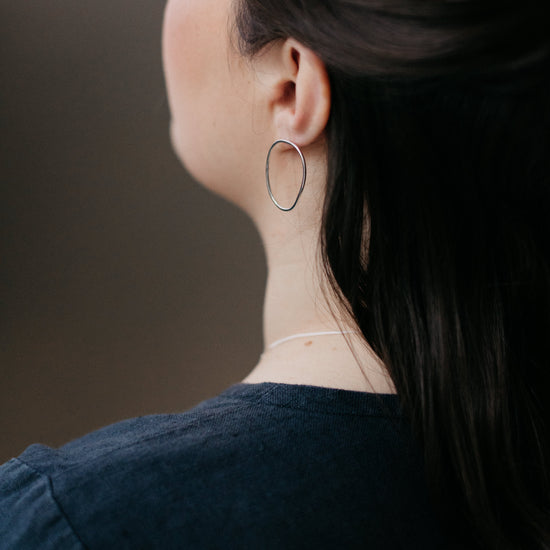 A pair of sterling silver oval earrings worn by a model