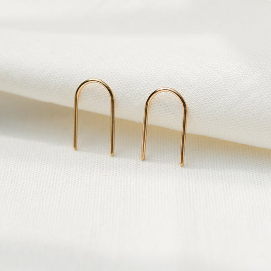 A pair of arch-shaped earrings made from silver and gold, displayed against a light background.