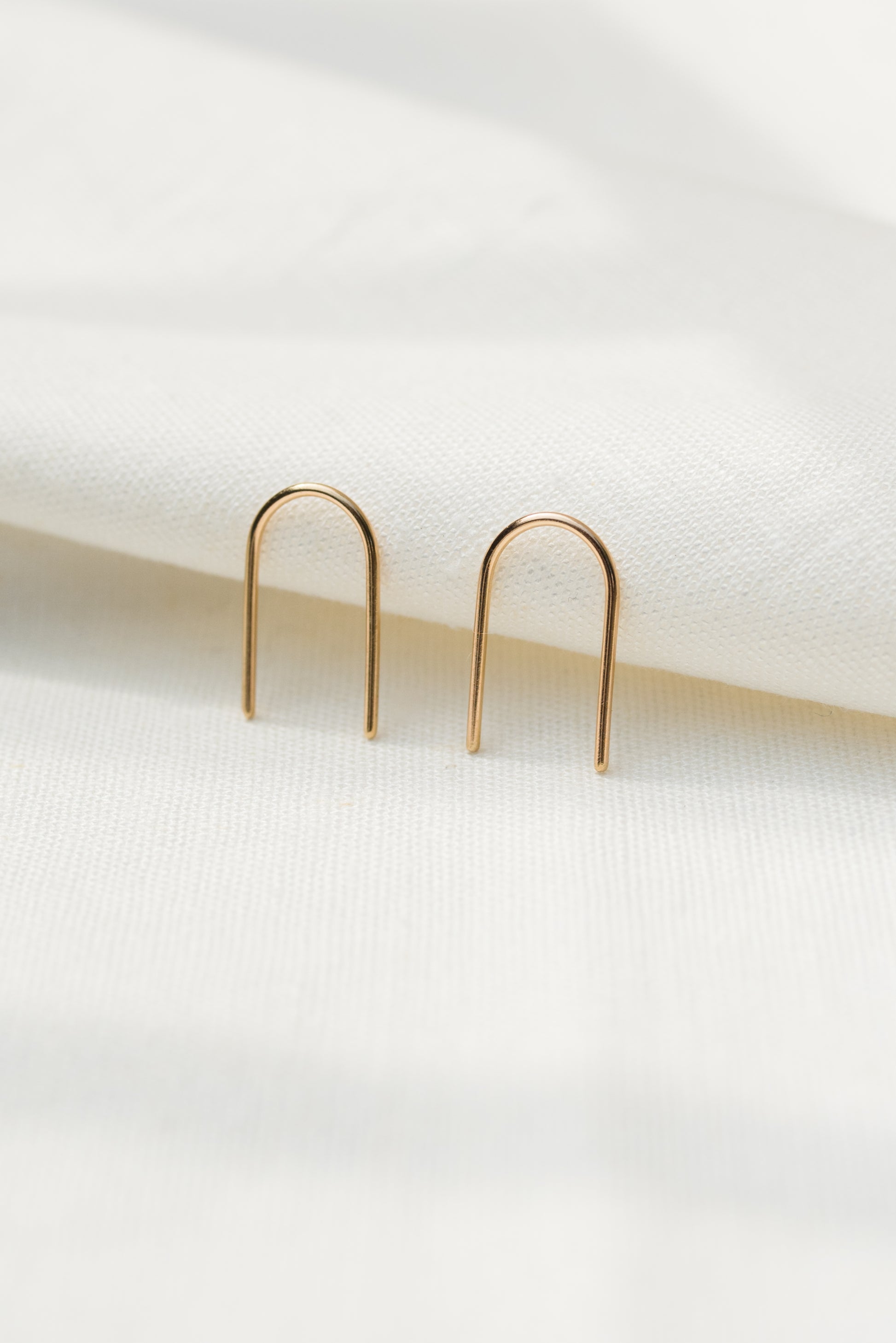 A pair of arch-shaped earrings made from silver and gold, displayed against a light background.