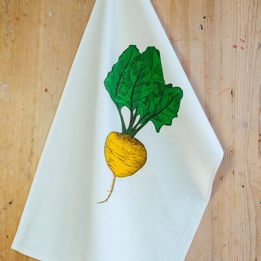 beetroot illustrated tea towel on a wooden surface