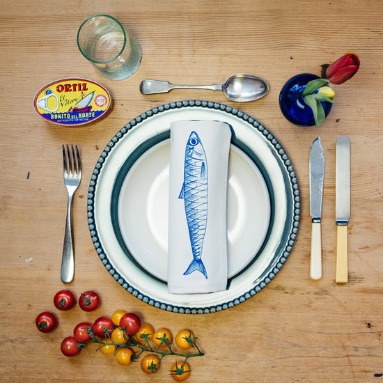 illustrated fish napkin laid on a plate with cutlery and various table settings