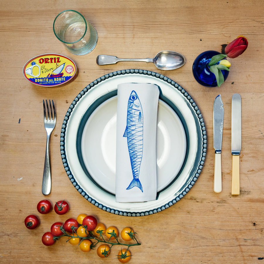 illustrated fish napkin laid on a plate with cutlery and various table settings