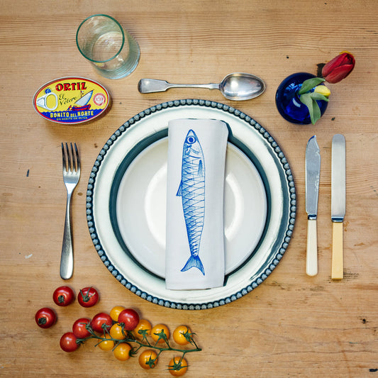 illustrated fish napkin laid on a plate with cutlery and various table settings