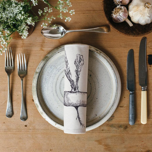 Root vegetable printed napkin on a plate and laid table with cutlery and garlic