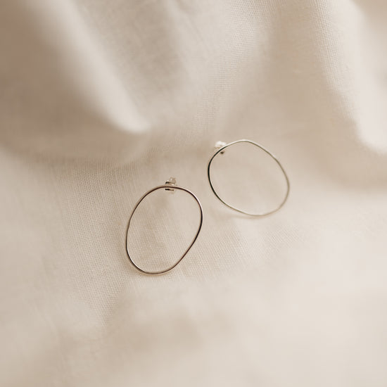 a pair of sterling silver free form oval hoop studs